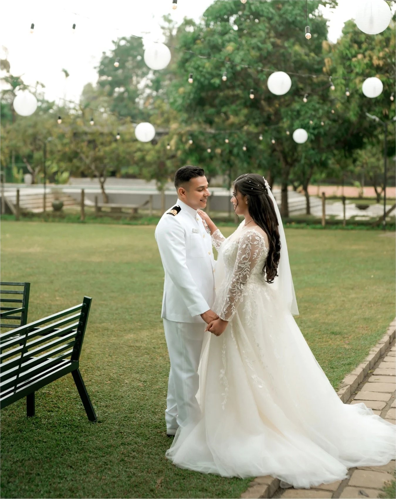 Bride and groom standing together beneath garden lights